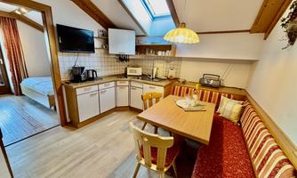 A cozy kitchen with a dining table and a seating area. The window lets in plenty of light and creates an inviting atmosphere.