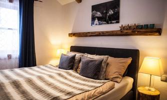 A cozy bedroom with a large bed and decorative pillows. A picture hangs on the wall, and the lighting creates a relaxing atmosphere.