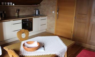 A cozy kitchen with a table that has a bowl and dishes on it. In the background, there are kitchen cabinets and a stove.