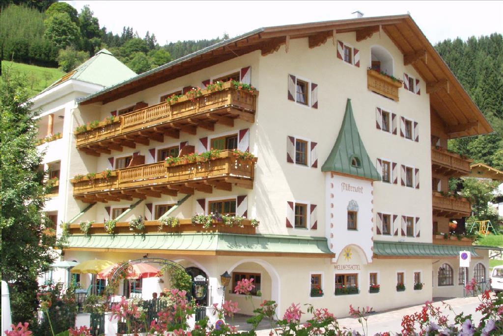 A charming hotel with wooden decorations and a balcony. Surrounded by green mountains and beautiful flowers.