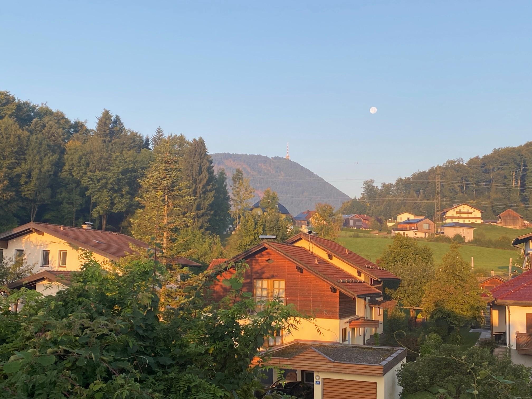 A picturesque village in the mountains with traditional houses. The sky is clear and the moon is visible.