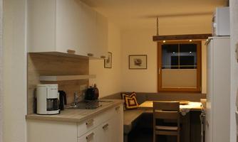 A modern kitchen with bright cabinets and a small seating area. The window lets in daylight and creates a friendly atmosphere.