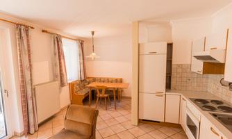 A bright kitchen corner with a dining area and a modern kitchen unit. The large windows provide plenty of daylight.