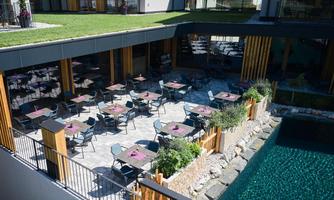 An inviting outdoor area of a restaurant with tables and chairs. In the background, a clear water reflection can be seen.