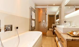 A modern bathroom with an elegant bathtub and a rain shower. The decor is bright and stylish, with natural wood and stone accents.