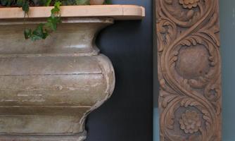 A decorative stone column with plants and a wooden art piece. The combination of nature and art gives the space warmth and style.
