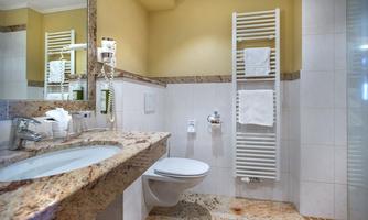 A modern bathroom with a granite wash basin and elegant fixtures. The walls are light, and the floor has a tiled look.