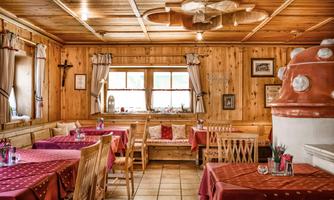 A cozy restaurant with wooden walls and tables covered in red. Large windows and decorative elements create an inviting atmosphere.