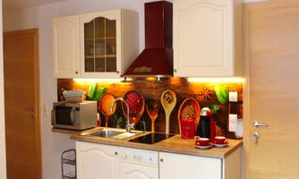 A modernly furnished kitchen with bright cabinets and a decorative wall design. There is a sink, a stove, and various kitchen appliances.