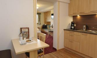A bright, modern kitchen unit with wooden cabinets and a cozy dining area. The room feels inviting and well-equipped.