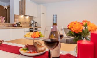 A cozy dining area with a table set for a nourishing dinner and red wine. In the background, a modern kitchen design and fresh flowers can be seen.