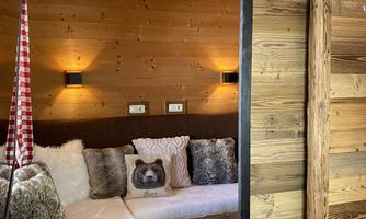 A cozy living space with wood paneling and pleasant lighting. There is a comfortable seating area with cushions and a decorative pillow in the shape of an animal.