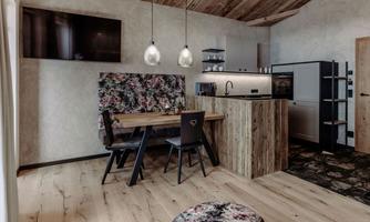 A modern kitchen with a wooden dining area and elegant lamps. The walls are tastefully decorated and the room design is cozy.
