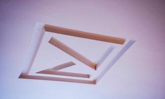 A modern ceiling installation with geometric shapes in neutral colors. The structure clearly stands out from the background.