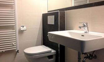 A modern bathroom with a sink and a toilet. There is a radiator and a mirror on the wall.