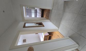 A bright hallway overlooking the two bedrooms. Access to the living/dining area, toilet, and bathroom.