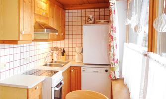 A cozy wooden kitchen with bright tiles and modern appliances. The space is well-lit and has an inviting atmosphere.