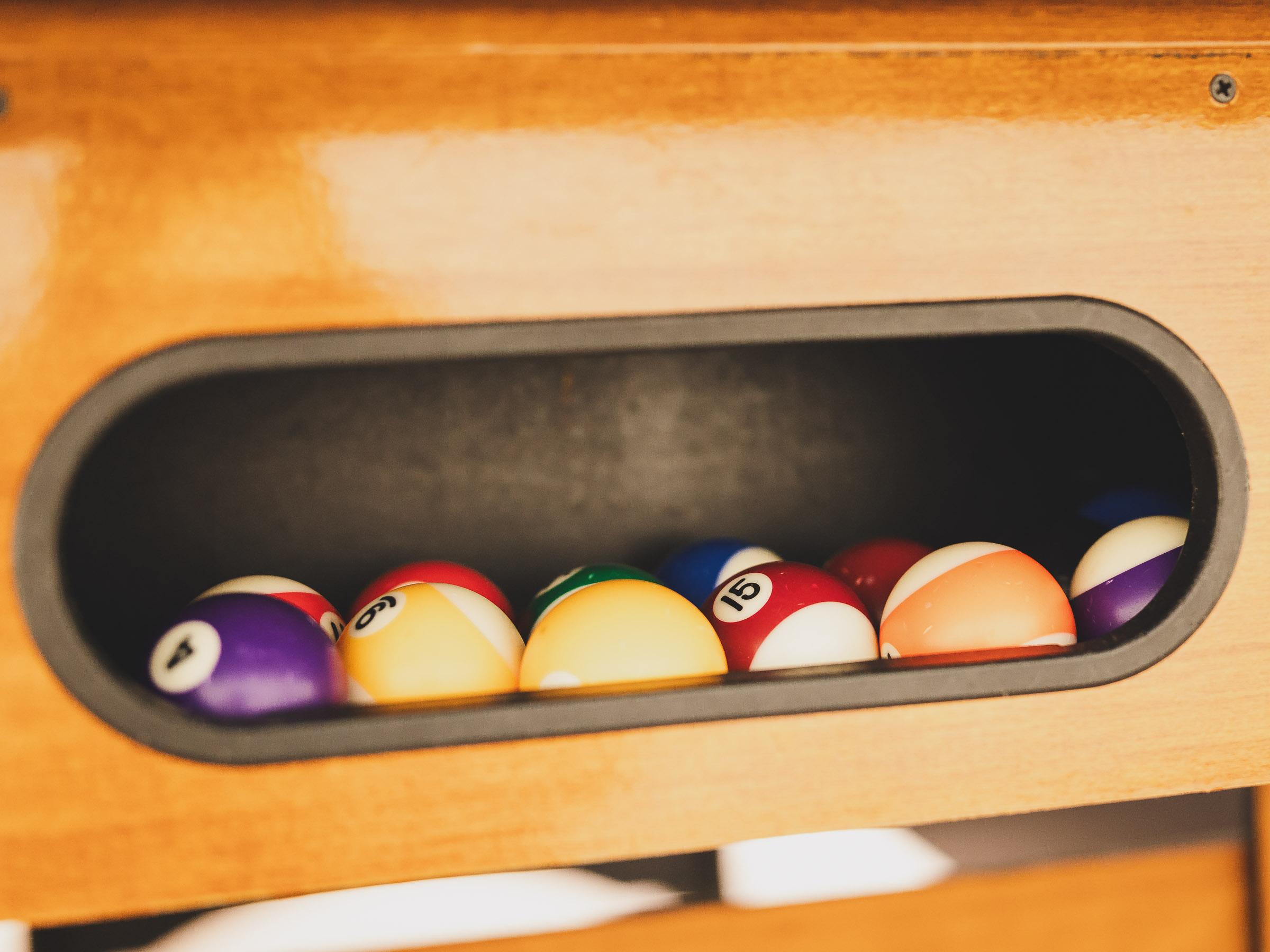 A selection of billiard balls is located in a compartment. The balls are arranged in different colors and numbers.
