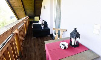 A cozy balcony with a wooden floor and a small table decoration. On the table, there is a lantern and a flower vase that create an inviting atmosphere.