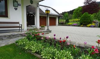 A beautiful garden with colorful tulips and well-maintained lawn. In the background, there is a house with a garage and a cozy seating area.
