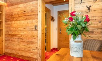 A cozy room with wooden paneling and a red carpet. A vase with fresh roses is on the table.