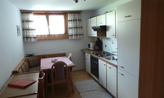 A modern kitchen with a dining area and a large window. The furniture is bright and inviting, perfect for shared meals.