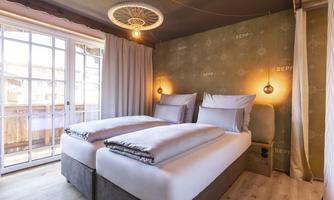 A modern room with two single beds and soft colors.  
Large windows provide plenty of natural light and a cozy atmosphere.