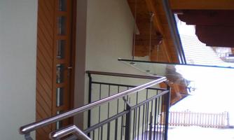 A bright hallway with a wood ceiling and a modern railing. The door is made of wood and probably leads outside.