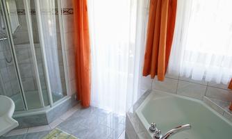 A bright bathroom with a whirlpool and a shower cabin. Curtains in shades of orange create a cozy atmosphere.