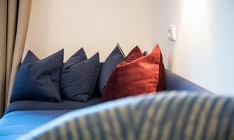 A cozy sofa with decorative cushions in various colors. The wall is simple and light, creating an inviting atmosphere.