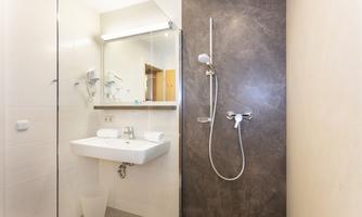 The bathroom is modernly designed with a shower and a sink. Bright walls and a simple decor create a pleasant atmosphere.