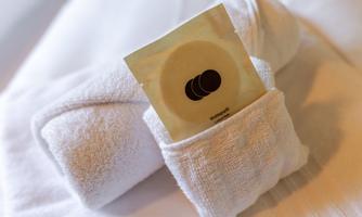 A clean, white towel is neatly folded. There is a small package with a logo placed inside.