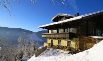 A charming chalet in the snow with a stunning view of the mountains. The surroundings are wintry and inviting.