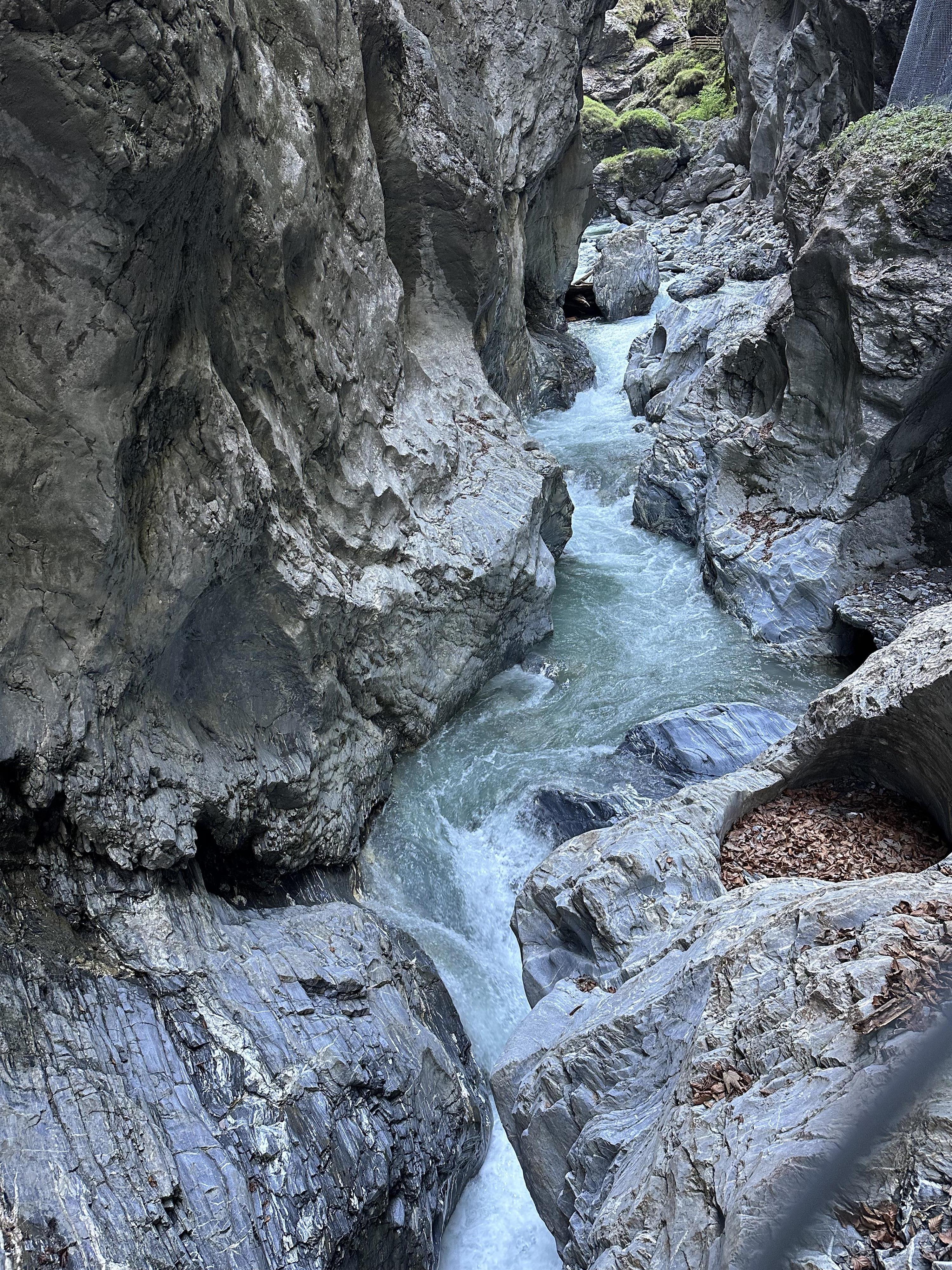A beautiful waterfall flowing between large rocks. The surroundings are natural and rocky.