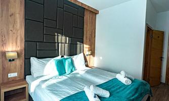 A modern bedroom with a double bed and elegant bed linen. The walls are decorated with wood and a stylish design.