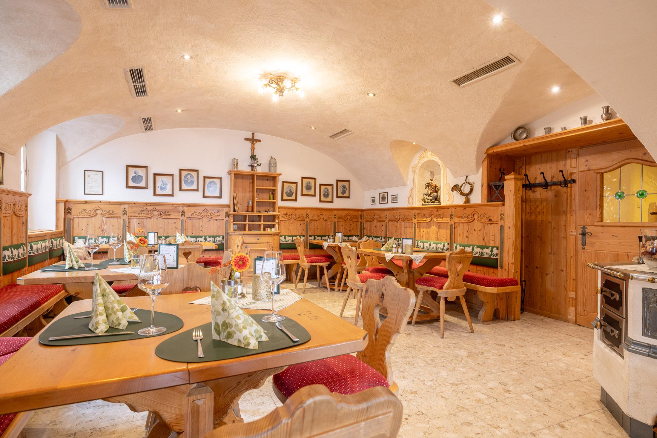 A cozy restaurant with wooden furniture and round tables. The walls are decorated with pictures and decorations, and the atmosphere is inviting.
