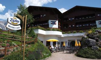An inviting bistro with a beautiful outdoor terrace. Surrounded by green plants and a clear sky.