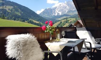 A beautiful balcony with a view of the mountains.  
On the table are flowers, a glass of wine, and a bottle.