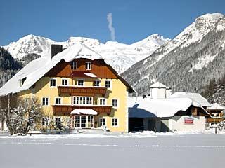 A beautiful house in the snow with a picturesque mountain landscape in the background. The surroundings are wintry and idyllic.