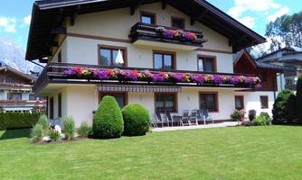 A beautiful, modern house with a balcony, adorned with colorful flowers. The landscaped garden is well-maintained and offers seating areas.