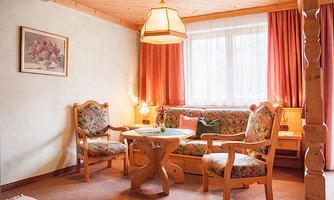 A cozy living room with a sofa and two chairs. The room has warm colors and plenty of natural light.
