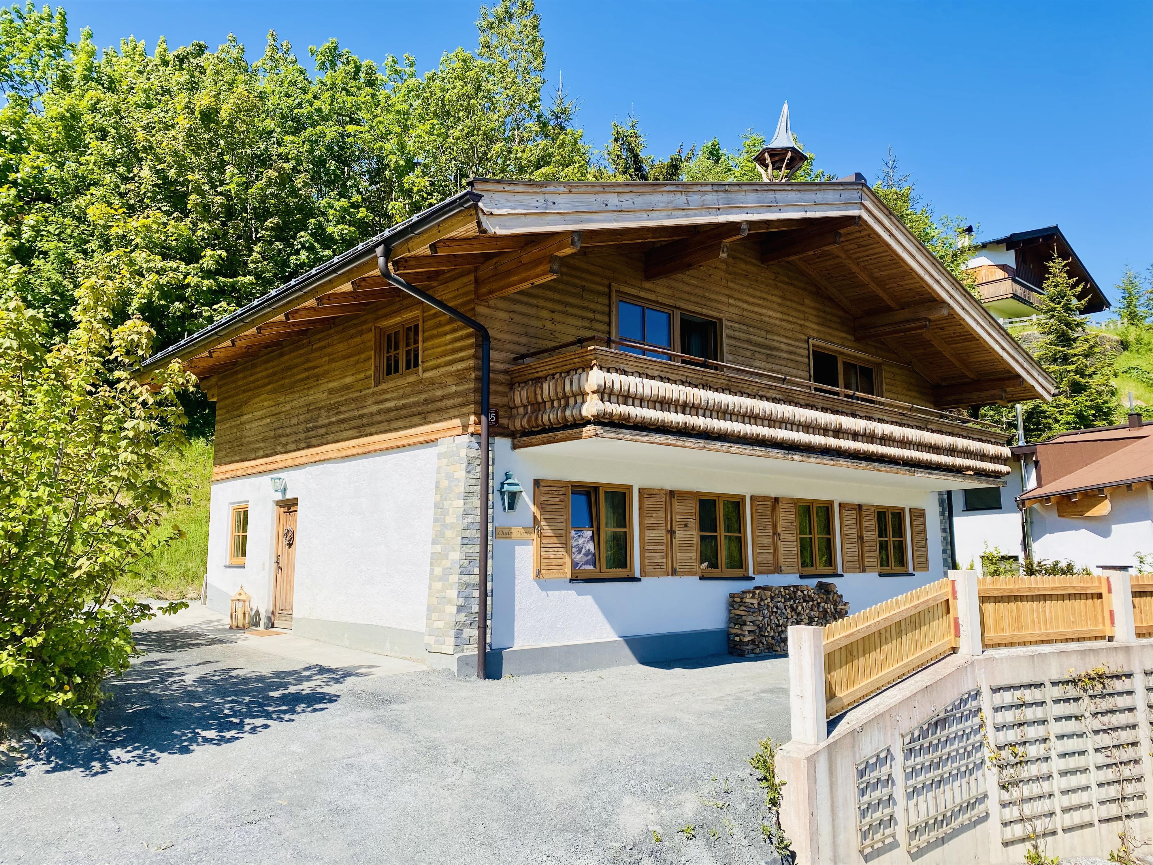 A beautiful wooden house surrounded by trees. The sky is blue and the day is sunny.