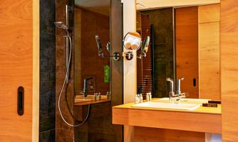 A modern bathroom with wooden elements. There is a shower and a sink that is stylishly and minimally designed.