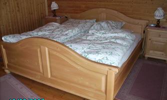 A cozy bedroom with a large wooden bed and striped bedspreads. Next to the bed are nightstands with lamps.