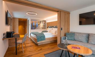 A modern hotel room with wooden paneling and a cozy seating area. The atmosphere is bright and inviting, perfect for relaxing.