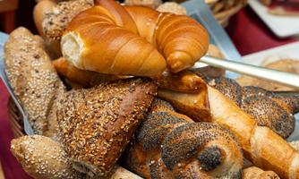 A basket full of fresh rolls and pretzels. The variety of baked goods invites you to indulge.