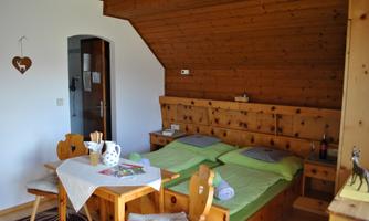 A cozy room with wood paneling, two beds, and a dining table. Beverages and snacks are ready on the table.