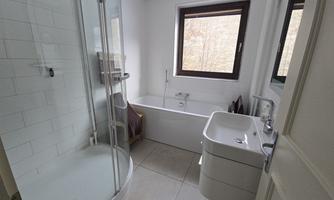 A modern bathroom with a shower and a bathtub and windows.