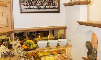A buffet with various breakfast options, including fresh fruit, pastries, and a selection of cold cuts. Behind the buffet hangs a picture of a group photo.