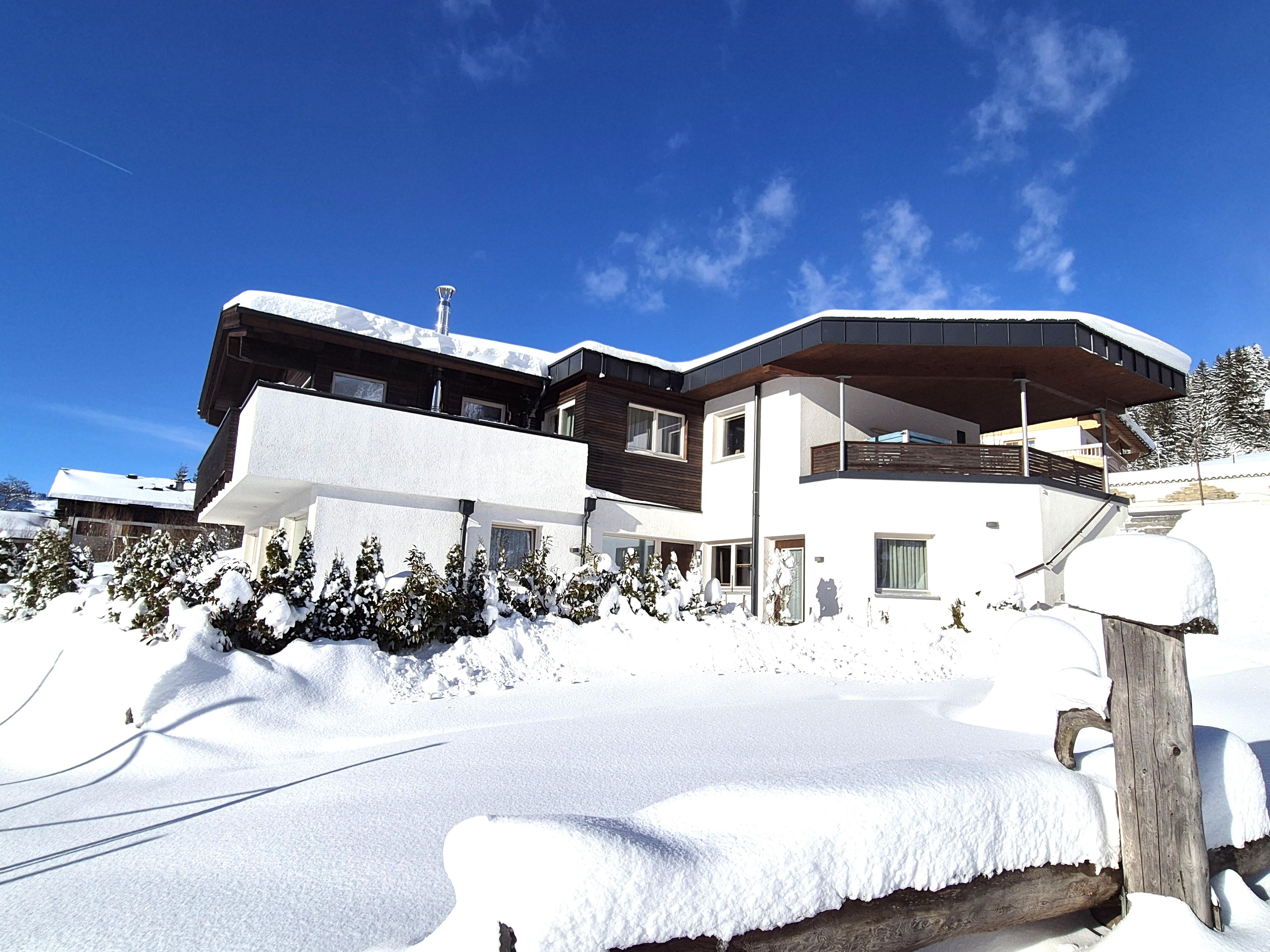 A modern house in winter, surrounded by fresh snow. The clear blue sky completes the winter landscape.